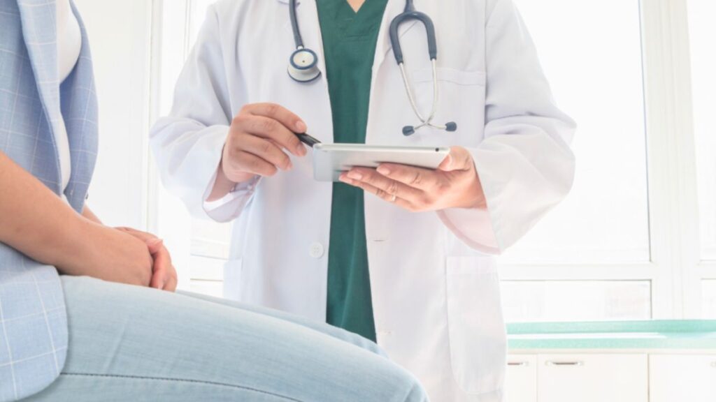 A doctor holds a tablet while a patient sits, discussing Functional Medicine Miami.