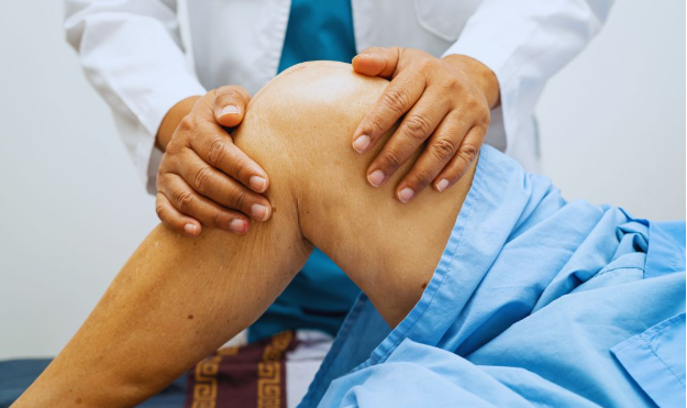 A healthcare professional examines a patient's knee, demonstrating hands-on assessment during a functional rheumatology session focused on early intervention for joint pain or inflammation.