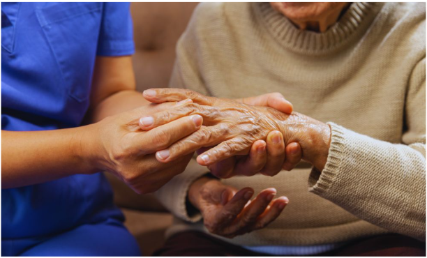 A healthcare provider examines the swollen hand of an elderly patient, illustrating a clinical moment related to gout and autoimmune disease care. The image reflects joint inflammation commonly seen in these conditions.
