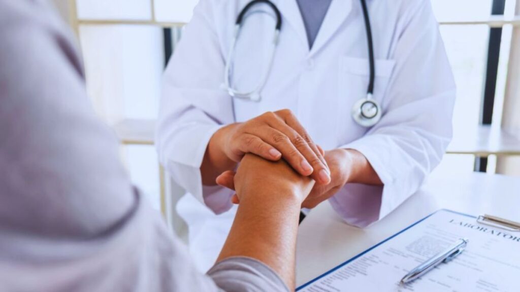 Doctor holding a patient’s hands during a rheumatology consultation.
