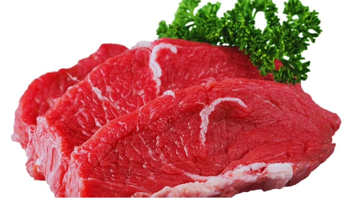 Raw marbled beef steaks garnished with parsley on a white background, illustrating red meat as a potential trigger for autoimmune disease flare-ups.